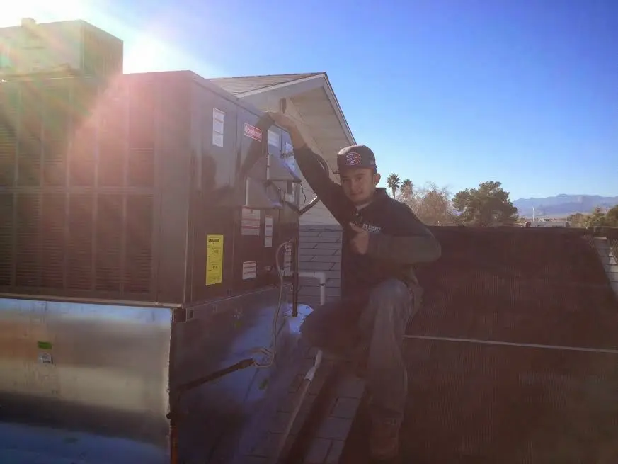 HVAC technician performing AC Tune-Up on a rooftop unit in Floyds Knobs
